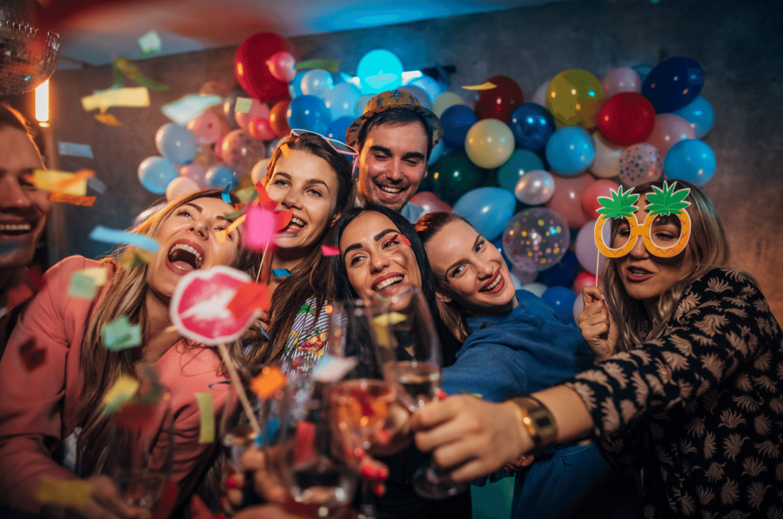 Grupa ljudi se zabavlja i slika s rekvizitima u photo boothu.